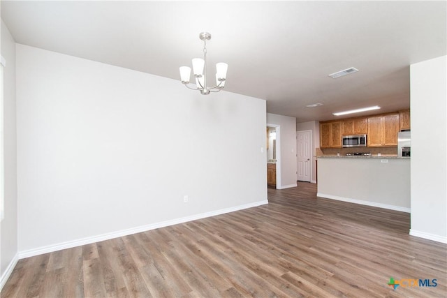 unfurnished living room featuring dark hardwood / wood-style flooring and a chandelier