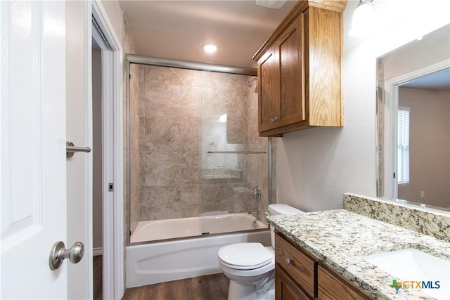 full bathroom with wood-type flooring, vanity, enclosed tub / shower combo, and toilet