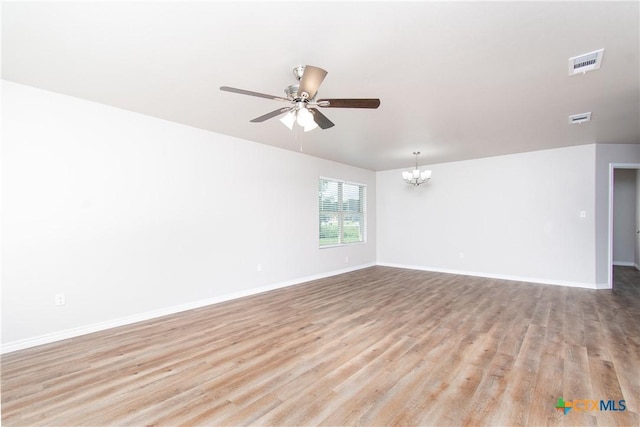 unfurnished room featuring ceiling fan with notable chandelier and light wood-type flooring