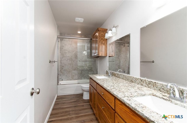 full bathroom featuring shower / bath combination with glass door, vanity, wood-type flooring, and toilet