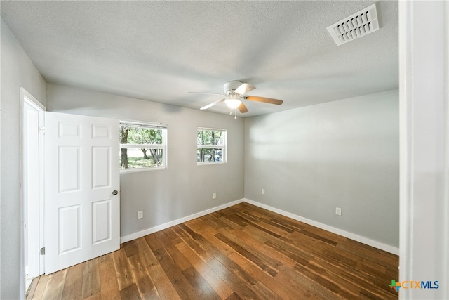 empty room featuring a textured ceiling, dark wood-type flooring, and ceiling fan