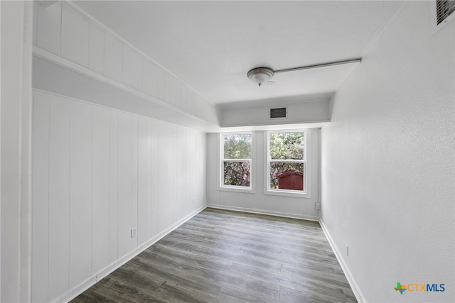 unfurnished room with wood walls and dark hardwood / wood-style floors