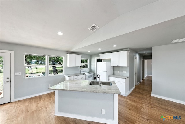 kitchen featuring a center island with sink, white cabinetry, white refrigerator, sink, and lofted ceiling