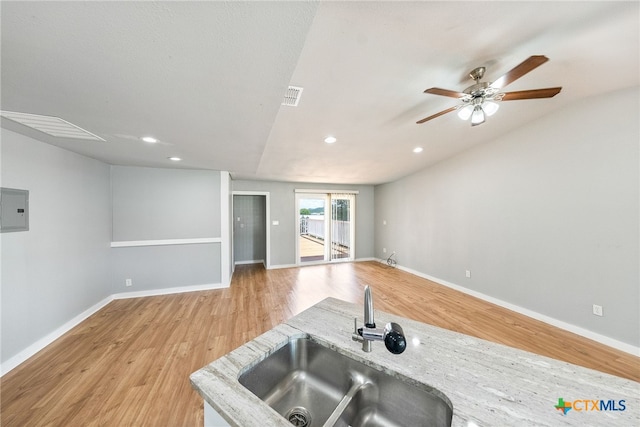 kitchen featuring light stone countertops, lofted ceiling, sink, and light hardwood / wood-style flooring