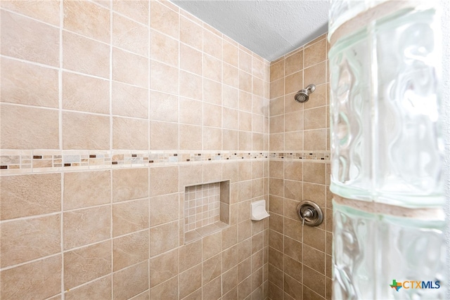 bathroom with tiled shower and a textured ceiling