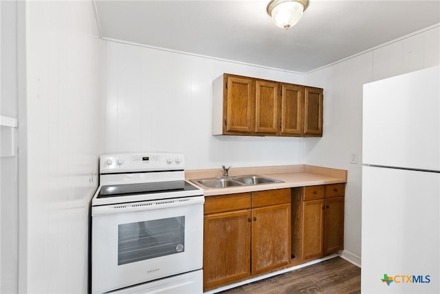 kitchen featuring wood walls, dark wood-type flooring, sink, and white appliances