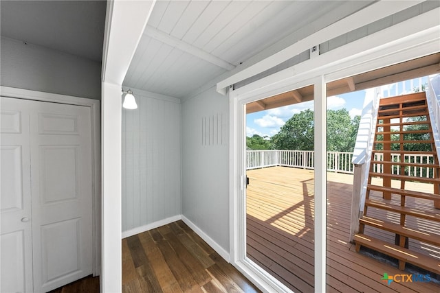 doorway with beamed ceiling, dark hardwood / wood-style floors, wood ceiling, and wood walls