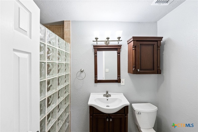 bathroom with walk in shower, vanity, a textured ceiling, and toilet