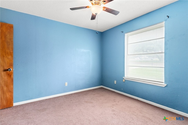 carpeted spare room featuring baseboards and ceiling fan