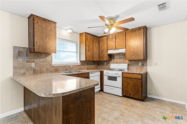 kitchen featuring a sink, white appliances, a peninsula, under cabinet range hood, and visible vents