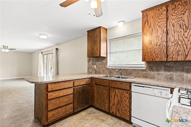 kitchen with a peninsula, a sink, backsplash, white appliances, and ceiling fan