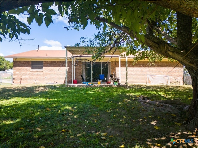 rear view of house featuring brick siding and a lawn