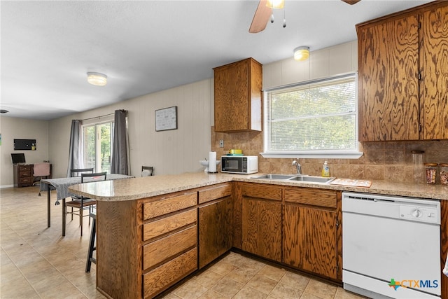 kitchen with backsplash, white appliances, sink, kitchen peninsula, and ceiling fan