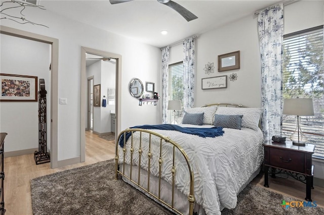 bedroom with ceiling fan, ensuite bathroom, and light wood-type flooring