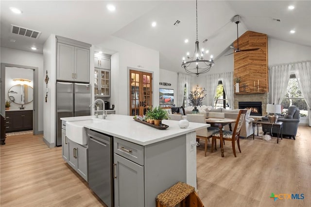 kitchen featuring gray cabinets, hanging light fixtures, plenty of natural light, an island with sink, and a stone fireplace