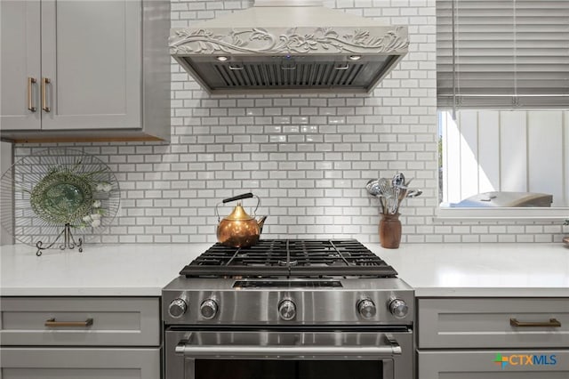 kitchen featuring stainless steel range with gas cooktop, gray cabinets, and custom exhaust hood