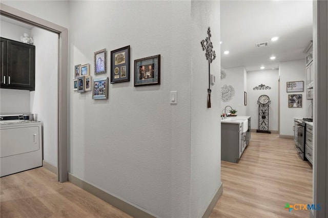 corridor featuring washer / clothes dryer, light hardwood / wood-style flooring, and sink