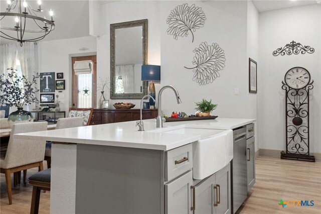 kitchen with dishwasher, a kitchen island with sink, gray cabinetry, and light wood-type flooring