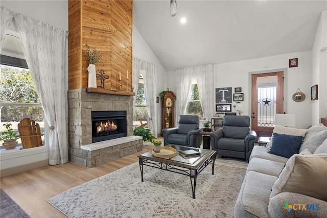 living room with a stone fireplace, plenty of natural light, and light hardwood / wood-style floors