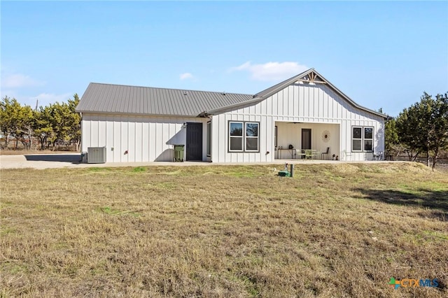 back of house with cooling unit and a yard