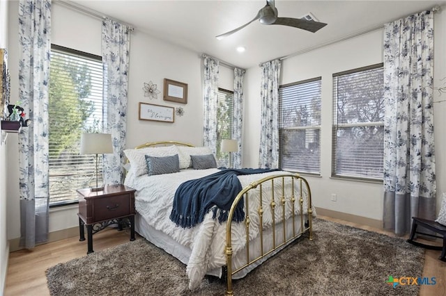 bedroom with ceiling fan, wood-type flooring, and multiple windows