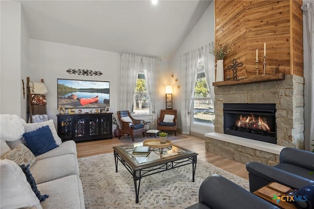 living room featuring high vaulted ceiling, light wood-type flooring, and a fireplace