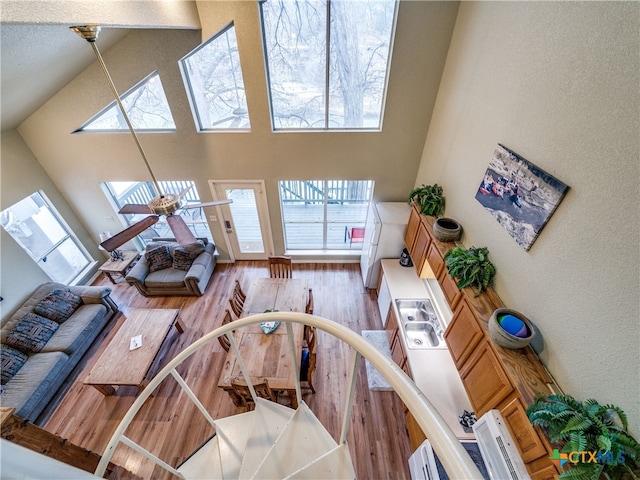 living room with ceiling fan, a skylight, high vaulted ceiling, and light wood-type flooring