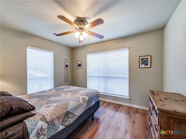 bedroom featuring ceiling fan, hardwood / wood-style floors, and a textured ceiling