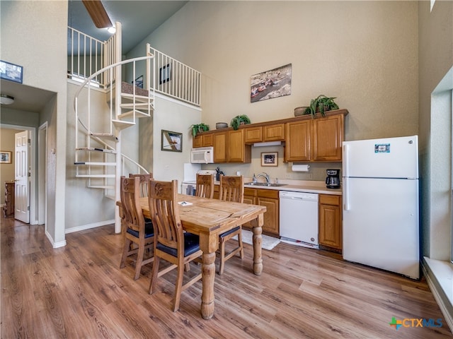 dining space featuring sink, light hardwood / wood-style floors, and a high ceiling