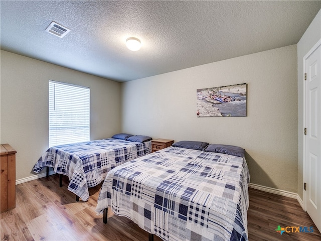 bedroom with hardwood / wood-style floors and a textured ceiling