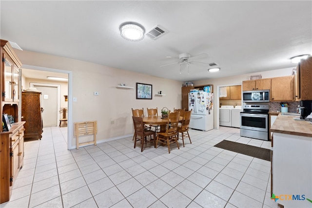 kitchen featuring appliances with stainless steel finishes, ceiling fan, light tile patterned floors, washing machine and dryer, and decorative backsplash