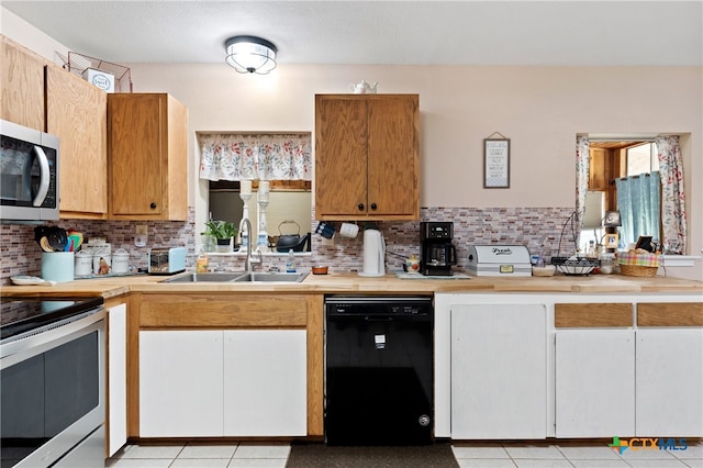 kitchen featuring backsplash, appliances with stainless steel finishes, sink, and light tile patterned flooring