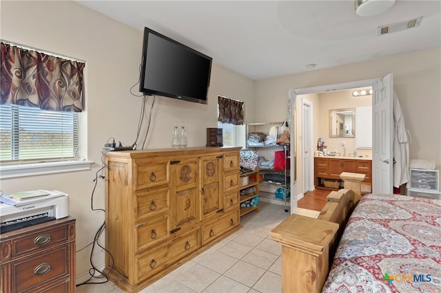 bedroom with ensuite bath and light tile patterned floors