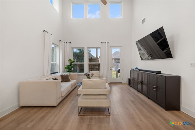 living room with light hardwood / wood-style floors and a high ceiling