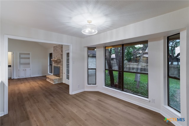 9215 Standing Creek Ln, San Antonio, TX 78230 - spare room with a chandelier, wood finished floors, baseboards, a brick fireplace, and vaulted ceiling