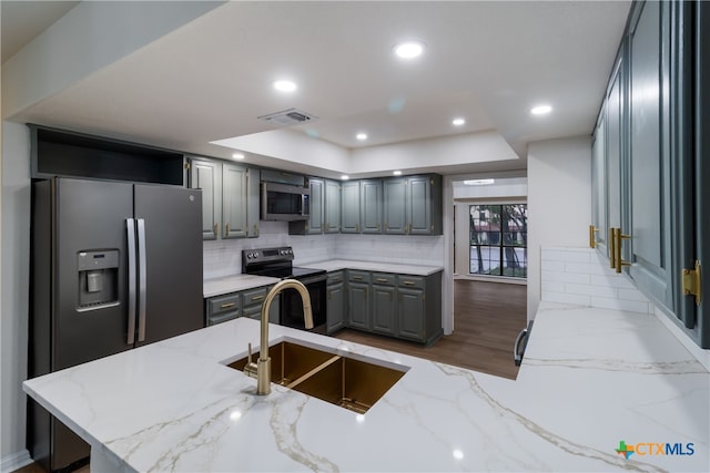 9215 Standing Creek Ln, San Antonio, TX 78230 - kitchen featuring appliances with stainless steel finishes, gray cabinetry, a sink, a tray ceiling, and light stone countertops