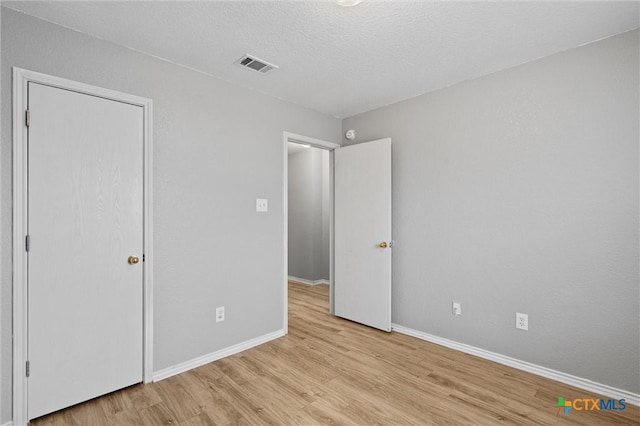 unfurnished bedroom with a textured ceiling and light hardwood / wood-style flooring