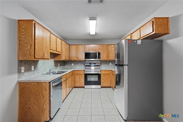 kitchen with decorative backsplash, appliances with stainless steel finishes, a textured ceiling, sink, and light tile patterned floors