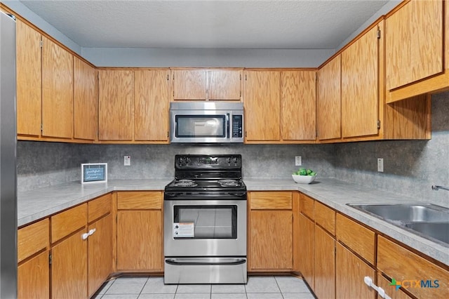 kitchen featuring light tile patterned floors, backsplash, stainless steel appliances, and sink