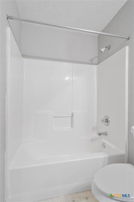 bathroom with washtub / shower combination, a textured ceiling, and toilet