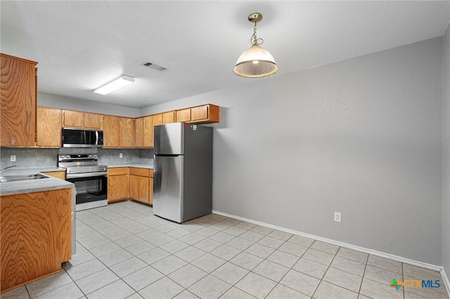 kitchen with sink, light tile patterned floors, appliances with stainless steel finishes, tasteful backsplash, and decorative light fixtures