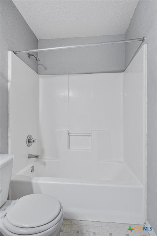 bathroom with a textured ceiling, shower / bathtub combination, and toilet