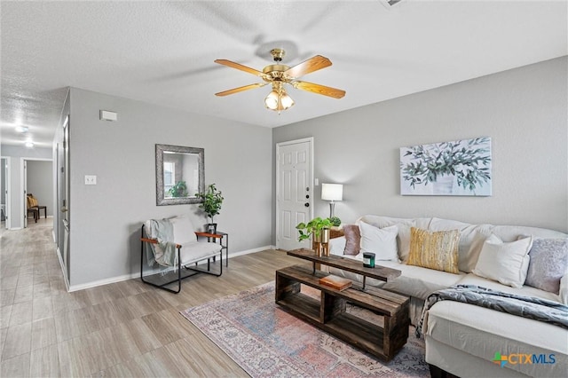 living room with ceiling fan and a textured ceiling