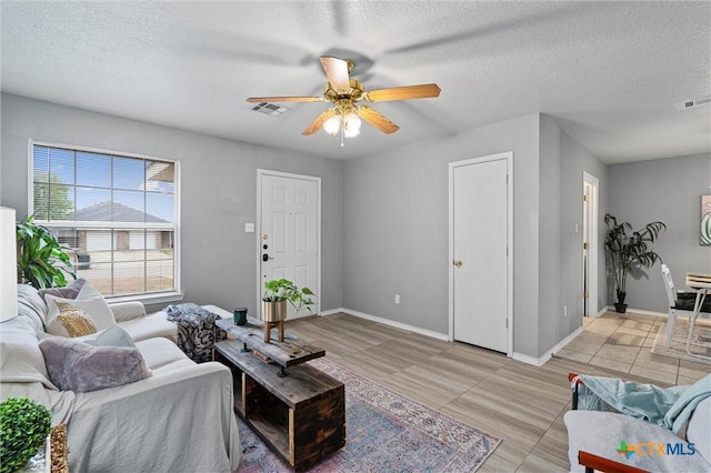 living room with a textured ceiling, ceiling fan, and light tile patterned flooring