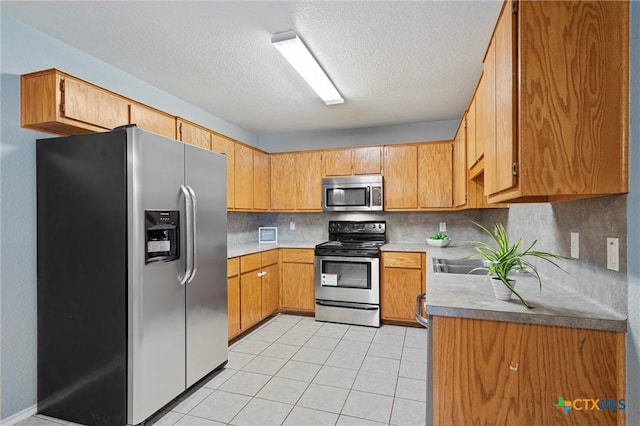 kitchen featuring tasteful backsplash, light tile patterned floors, a textured ceiling, and appliances with stainless steel finishes