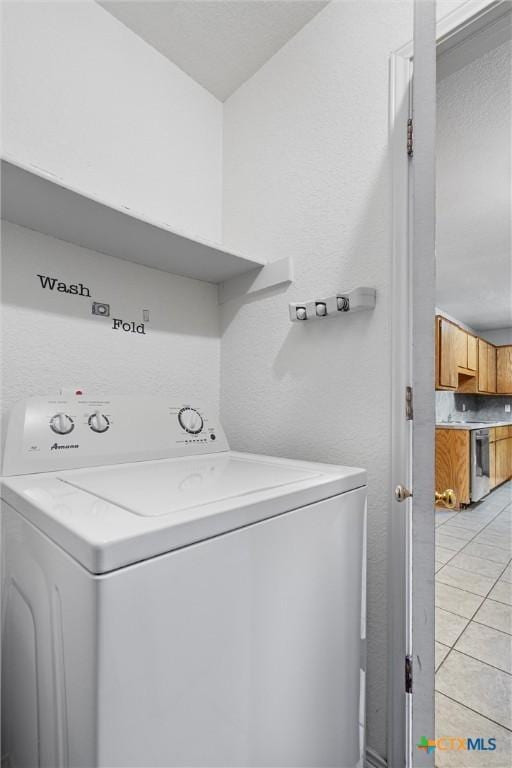 laundry area with washer / clothes dryer and light tile patterned flooring