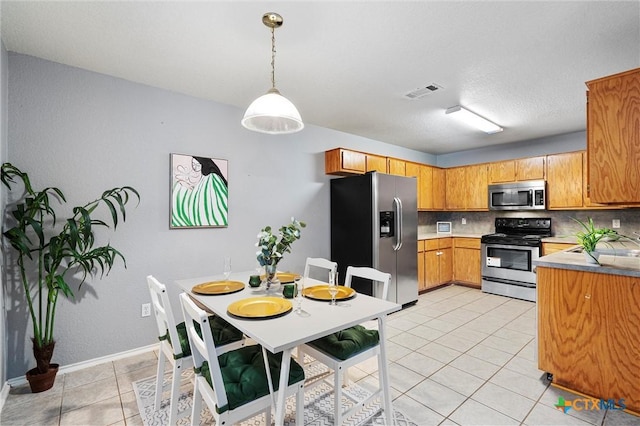 kitchen featuring sink, decorative backsplash, light tile patterned floors, decorative light fixtures, and stainless steel appliances