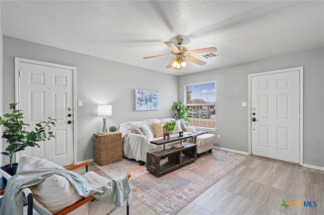 living room with ceiling fan and a textured ceiling