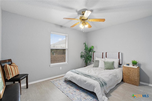 bedroom with hardwood / wood-style floors, ceiling fan, and a textured ceiling