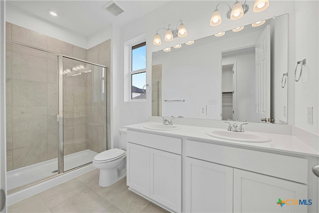 bathroom with tile patterned floors, a shower with door, vanity, and toilet